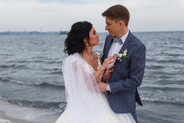 Sonriendo novios novios en el día de la boda al aire libre en la playa del río