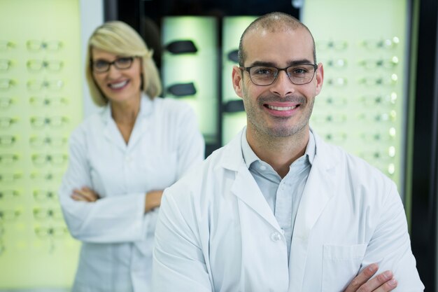 Sonriendo optometristas de pie con los brazos cruzados