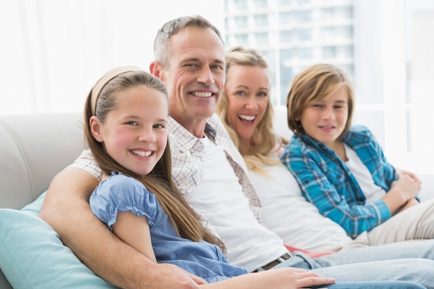 Sonriendo padres e hijos sentados juntos en el sofá