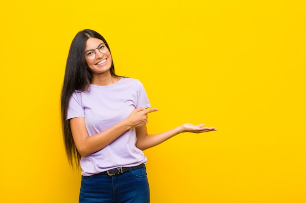 sonriendo, sintiéndose feliz, despreocupado y satisfecho, señalando el concepto o la idea en el espacio de la copia en el lateral