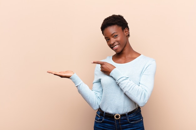 sonriendo, sintiéndose feliz, despreocupado y satisfecho, señalando el concepto o la idea en el espacio de la copia en el lateral
