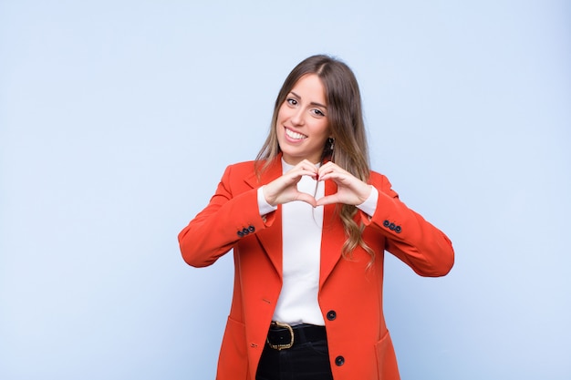 sonriendo y sintiéndose feliz, lindo, romántico y enamorado, haciendo forma de corazón con ambas manos