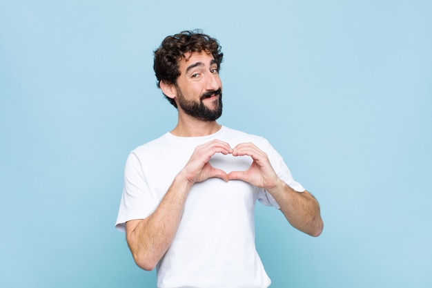 sonriendo y sintiéndose feliz, lindo, romántico y enamorado, haciendo forma de corazón con ambas manos