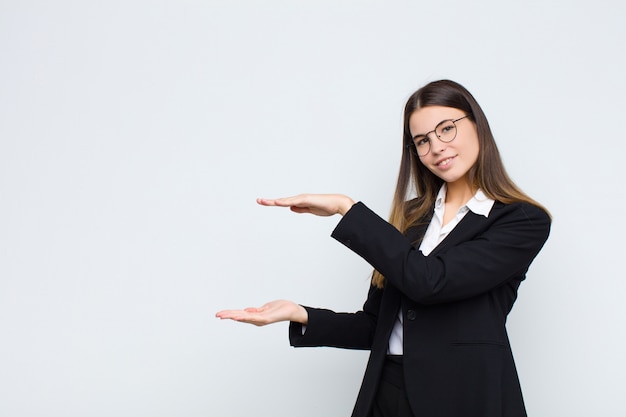 sonriendo, sintiéndose feliz, positivo y satisfecho, sosteniendo o mostrando un objeto o concepto en el espacio de la copia