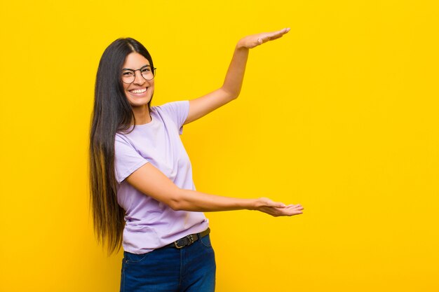 sonriendo, sintiéndose feliz, positivo y satisfecho, sosteniendo o mostrando un objeto o concepto en el espacio de la copia