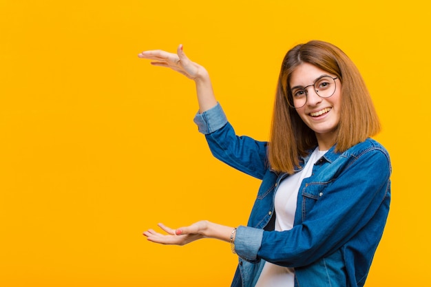 sonriendo, sintiéndose feliz, positivo y satisfecho, sosteniendo o mostrando un objeto o concepto