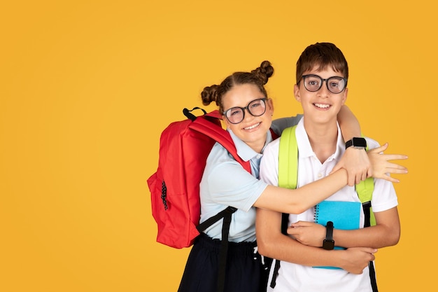 Sonriente adolescente caucásico inteligente con gafas abrazando a su novio alumno disfruta del estilo de vida