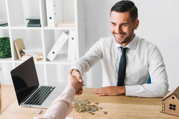 Sonriente agente inmobiliario agitando la mano del cliente