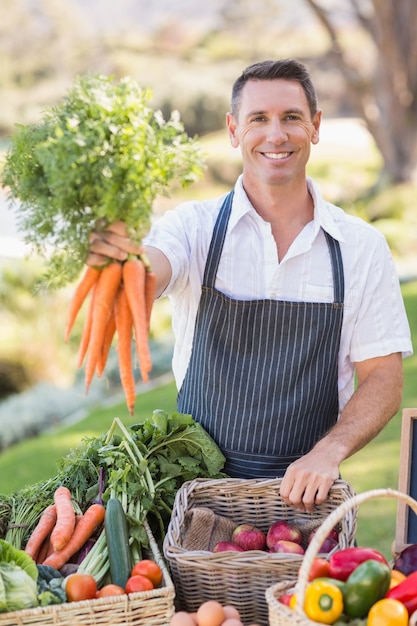 Sonriente agricultor entregando un manojo de zanahorias