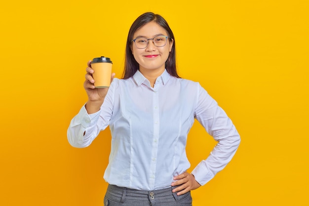 Sonriente y alegre mujer de negocios asiática con camisa blanca sosteniendo una taza de café recién comprada