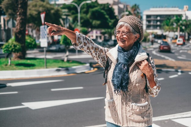 Sonriente anciana caucásica cruzando la calle caminando en un soleado centro de la ciudad