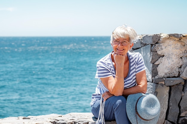 Sonriente anciana caucásica sentada al aire libre en vacaciones de verano en el mar Sonriendo expresando buen humor