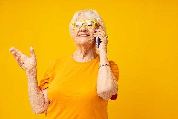 Sonriente anciana estilo de vida feliz en camisetas amarillas con emociones de primer plano del teléfono