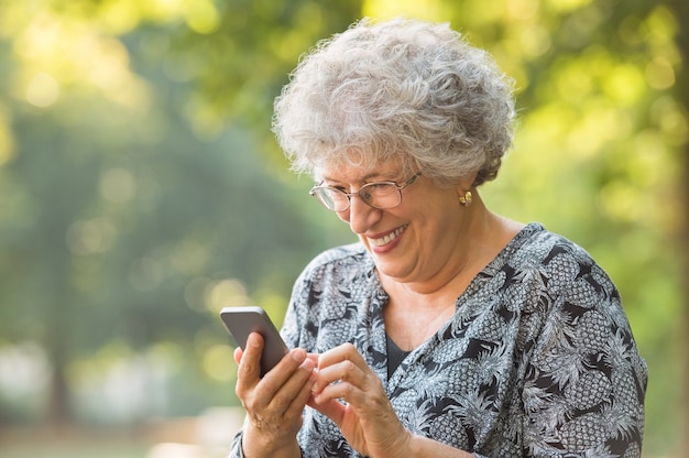 Foto sonriente anciana con un teléfono inteligente