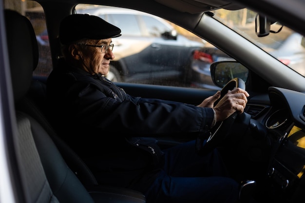 Sonriente anciano feliz en el coche nuevo