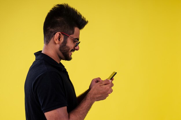 Foto sonriente apuesto hombre indio fotografiando selfie en estudio de fondo amarillo.