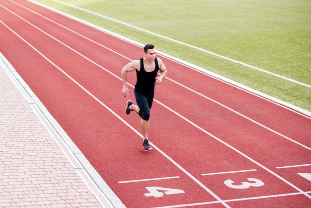 Sonriente atleta masculino corredor en la línea de llegada