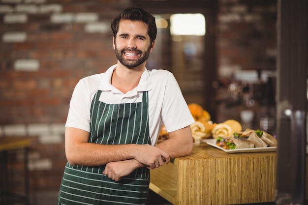 Sonriente barista apoyándose en el mostrador