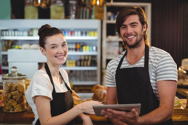 Sonriente camarero y camarera con tableta digital en el mostrador