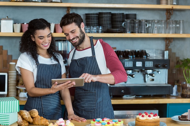 Sonriente camarero y camarera con tableta digital en el mostrador