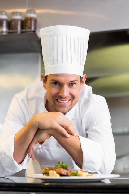 Sonriente chef masculino con comida cocinada en la cocina