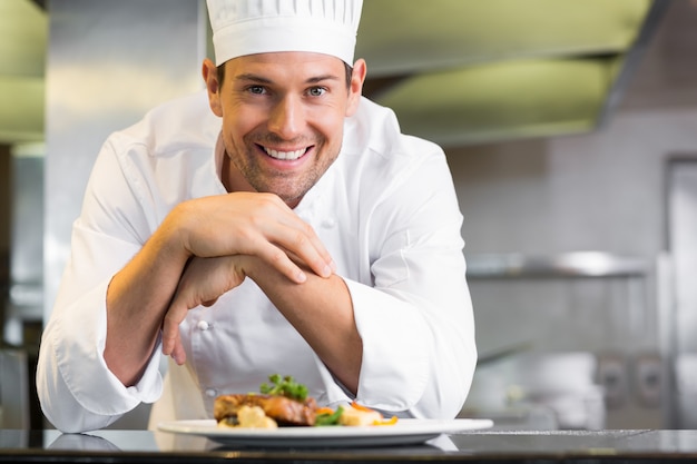 Sonriente chef masculino con comida cocinada en la cocina