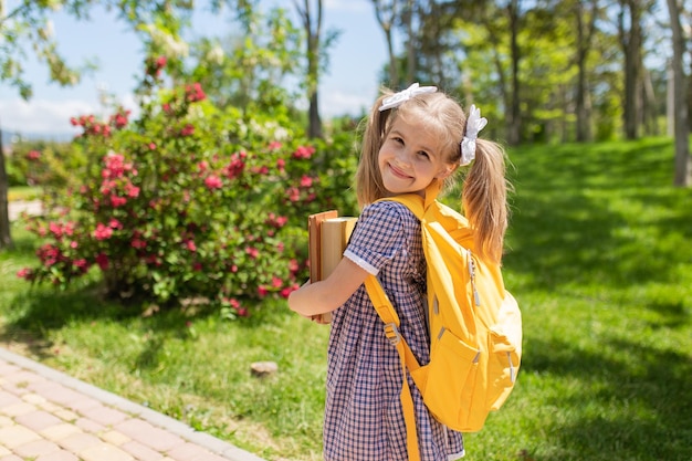 Sonriente colegiala linda en uniforme con mochila escolar regreso a la escuela el 1 de septiembre