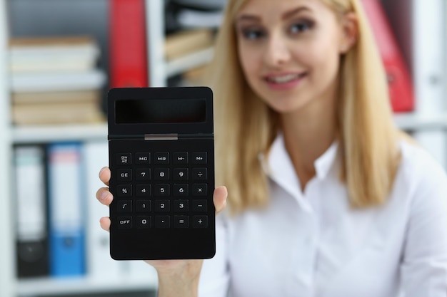 Sonriente contador empresaria sosteniendo la calculadora en la mano demuestra pantalla