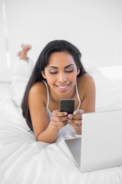 Sonriente contenido mujer mensajes de texto con su teléfono inteligente