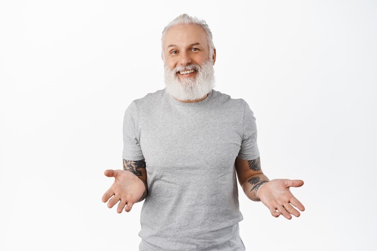 Sonriente y despreocupado anciano hipster extendió las manos hacia los lados, encogiéndose de hombros sin darse cuenta, luciendo descuidado y feliz, no sé nada, no tengo idea, parado sobre una pared blanca
