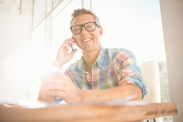 Sonriente diseñador casual con una llamada telefónica