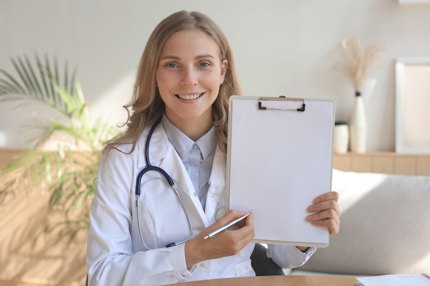 Sonriente doctora atractiva hablando a la cámara con el paciente.