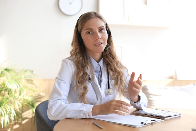 Sonriente doctora atractiva hablando a la cámara con el paciente.