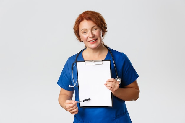 Sonriente doctora profesional, médica en matorrales mostrando prescripción en el portapapeles, apuntando al papel, dar recomendaciones o prescribir tratamiento.