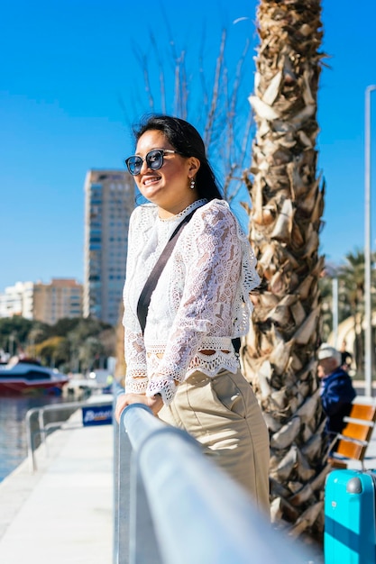 Sonriente empresaria asiática en traje con puerto en el fondo