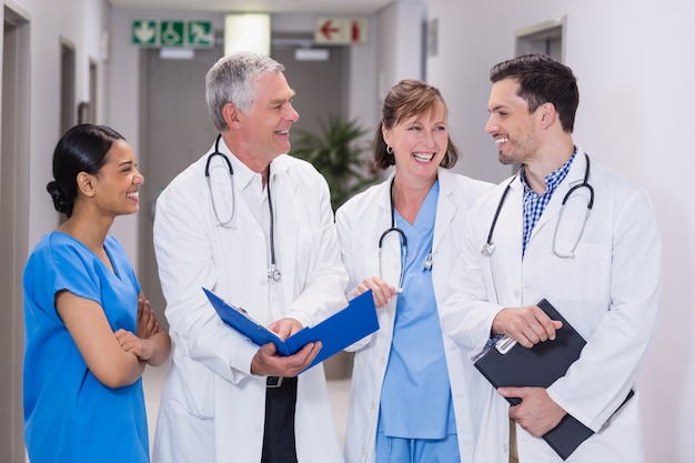 Sonriente enfermera y médicos discutiendo sobre portapapeles