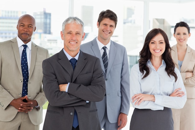 Sonriente equipo de negocios de pie delante de una ventana brillante