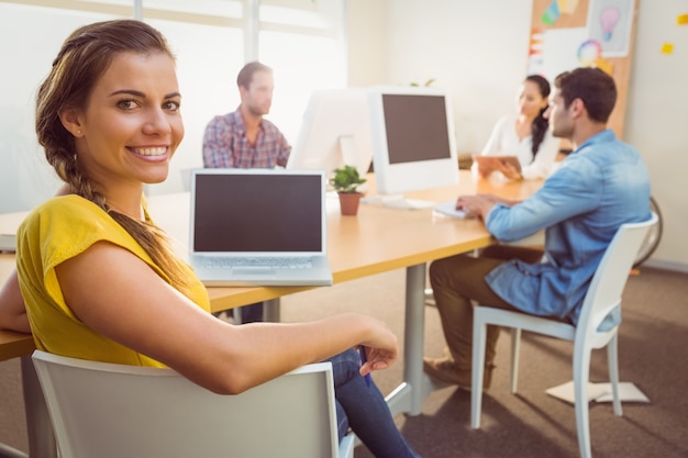 Sonriente equipo de negocios trabajando en computadoras portátiles