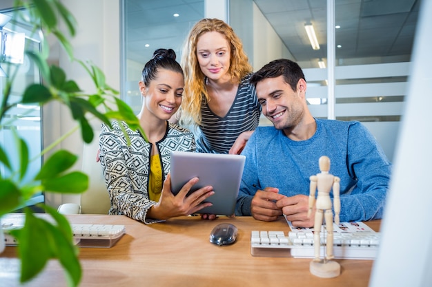 Sonriente equipo de negocios trabajando junto con tableta