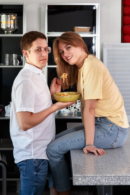 Sonriente esposo amoroso alimentando a su esposa joven pareja disfrutando de un momento tierno cita romántica divirtiéndose comiendo cocina japonesa familia feliz pasando el fin de semana gratis en la cocina moderna