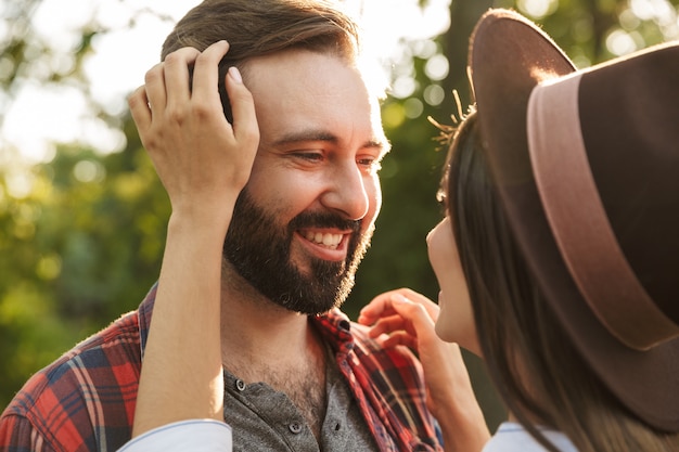 una sonriente feliz feliz complacido romántico joven pareja amorosa caminando al aire libre en un bosque de parque natural verde besos.