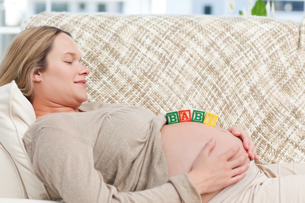 Sonriente futura mamá con letras de bebé en el vientre