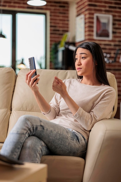 Sonriente hermosa mujer asiática auténtica en la videollamada de tecnología web de Internet en línea renunciando a la cámara, estilo de vida de ocio en el hogar comunicación web digital webcam chat freelacer en casa