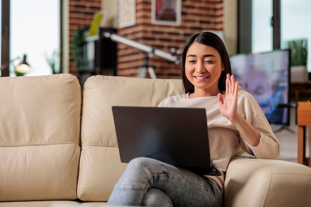 Sonriente hermosa mujer asiática auténtica en la videollamada de tecnología web de Internet en línea renunciando a la cámara, estilo de vida de ocio en el hogar comunicación web digital webcam chat freelacer en casa