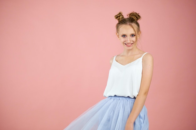 Foto sonriente hermosa mujer joven en mini vestido rosado posando con las manos en la barbilla tres cuartos de longitud de estudio disparado en fondo turquesa