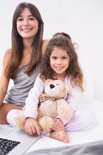 Sonriente hija y madre con laptop