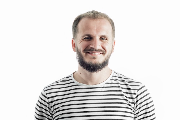 Sonriente hombre adulto con barba en una camiseta a rayas. 30-35 años. Aislado en blanco.