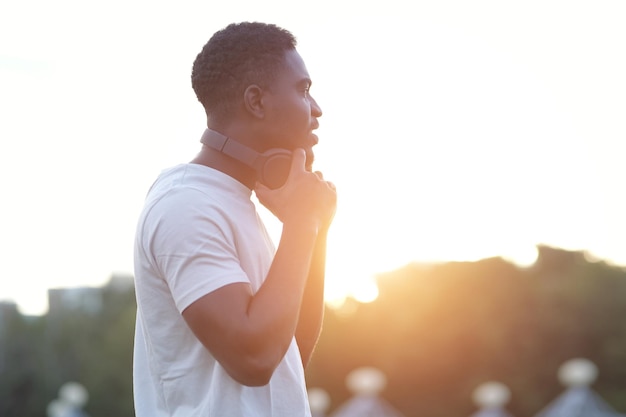 Sonriente hombre afroamericano con auriculares negros camina en Green Park