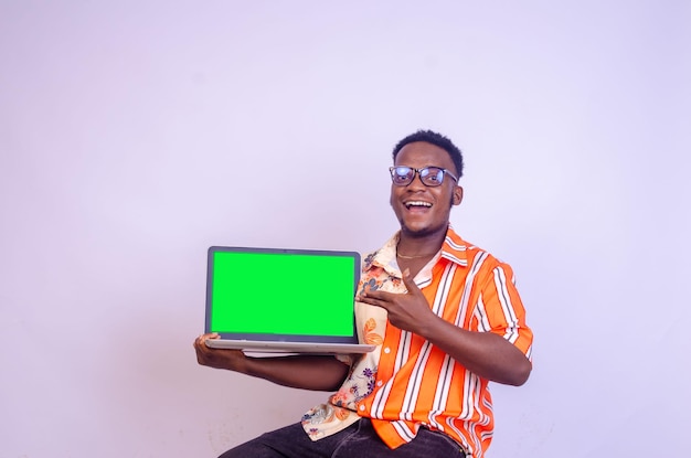 Sonriente hombre afroamericano en camiseta negra casual aislada sobre fondo blanco Concepto de estilo de vida de la gente Maqueta espacio de copia Señalar con el dedo índice en la computadora portátil con pantalla vacía en blanco