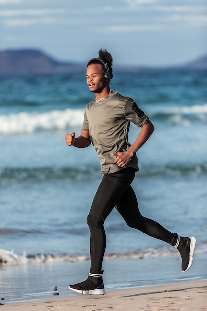 Sonriente hombre afroamericano corriendo cerca del mar